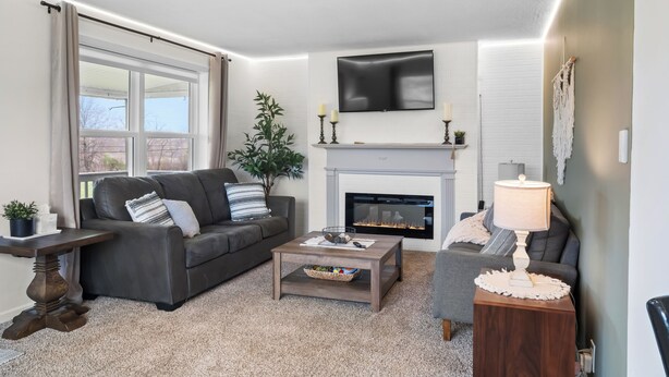A living room with a fireplace, a sofa, a coffee table, and a TV mounted on the wall.