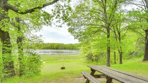 Ein Picknicktisch in einem Park mit einem See und Bäumen im Hintergrund.