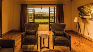 Una habitación con dos sillones estampados, una mesita redonda y un ventanal con vistas al paisaje.