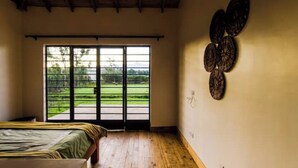Un dormitorio con un ventanal grande, una cama, suelo de madera y un adorno en la pared.