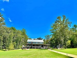 A two-story house with a covered porch, surrounded by a well-maintained lawn and trees. - LOWER Level of "Your Big Lake House" - Firepit, Kayaks, HotTub, etc.  (Cedar Bluff)