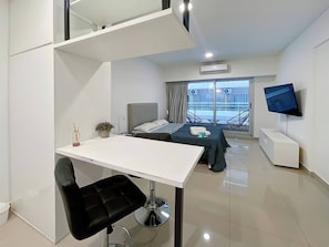 A modern hotel room with a bed, a desk, a chair, a TV, and a balcony with a view. - Studio Pool Balcony San Telmo (Buenos Aires)