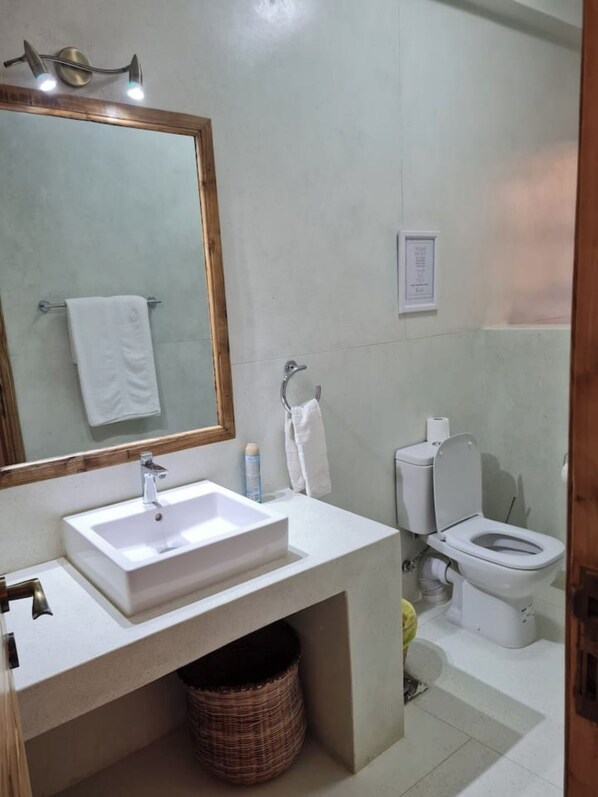 A bathroom with a white sink, mirror, and toilet.