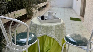 A small outdoor seating area with a table and chairs, a white pitcher, a cup, and a tray. - Dar khouaja

 (Mahdia)