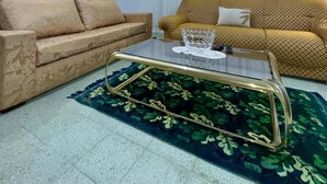 A living room with two sofas, a glass coffee table, a mirror, and a patterned rug. - Dar khouaja

 (Mahdia)