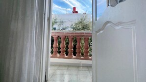 An open doorway leading to a balcony with a view of the sky and a red object on the roof. - Dar khouaja

 (Mahdia)