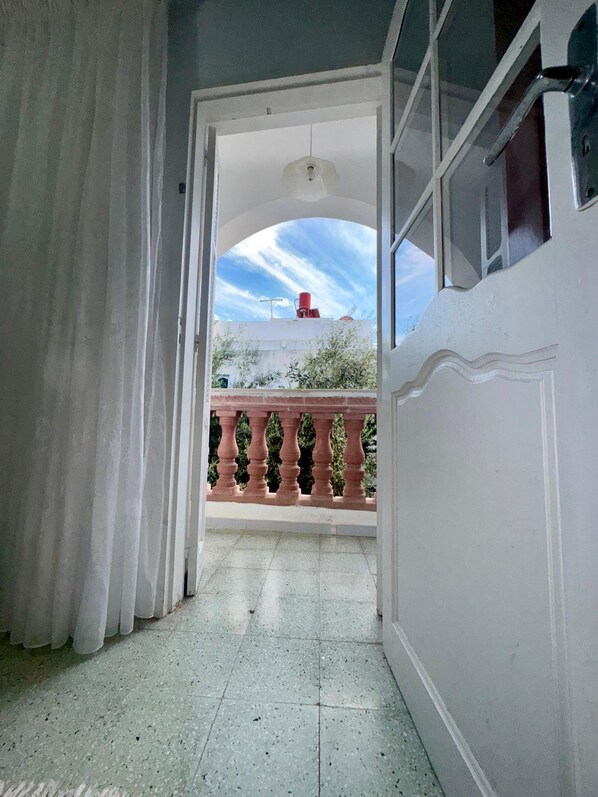 An open doorway leading to a balcony with a view of the sky and a red object on the roof. - Dar khouaja
(Mahdia)