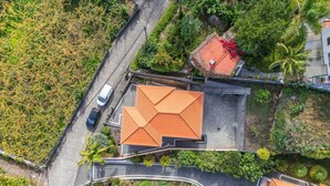 An aerial view of a residential area with terraced houses, a curved road, and a white car parked on the street. - Palm Tree House by Homie (São Vicente)