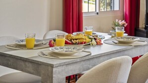 A breakfast table set with plates, glasses of orange juice, and a croissant. - Palm Tree House by Homie (São Vicente)