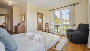 A bedroom with a bed, a chair, a dresser, and a large window. - Palm Tree House by Homie (São Vicente)