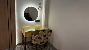 Une petite salle de bain moderne avec un miroir rond, un meuble-lavabo en verre et une chaise à motifs floraux.