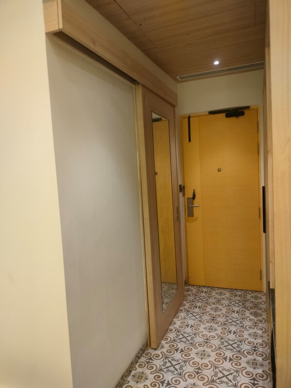 A hallway with a patterned floor, a wooden door, and a yellow door. - Hotel The Raghavas' (Faizabad)