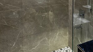 Une salle de bain moderne dotée d’une douche à parois de verre, de carreaux de marbre et d’une cloison en verre.