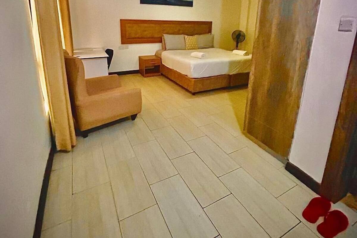 A hotel room with a bed, a chair, a bedside table, and a nightstand.
