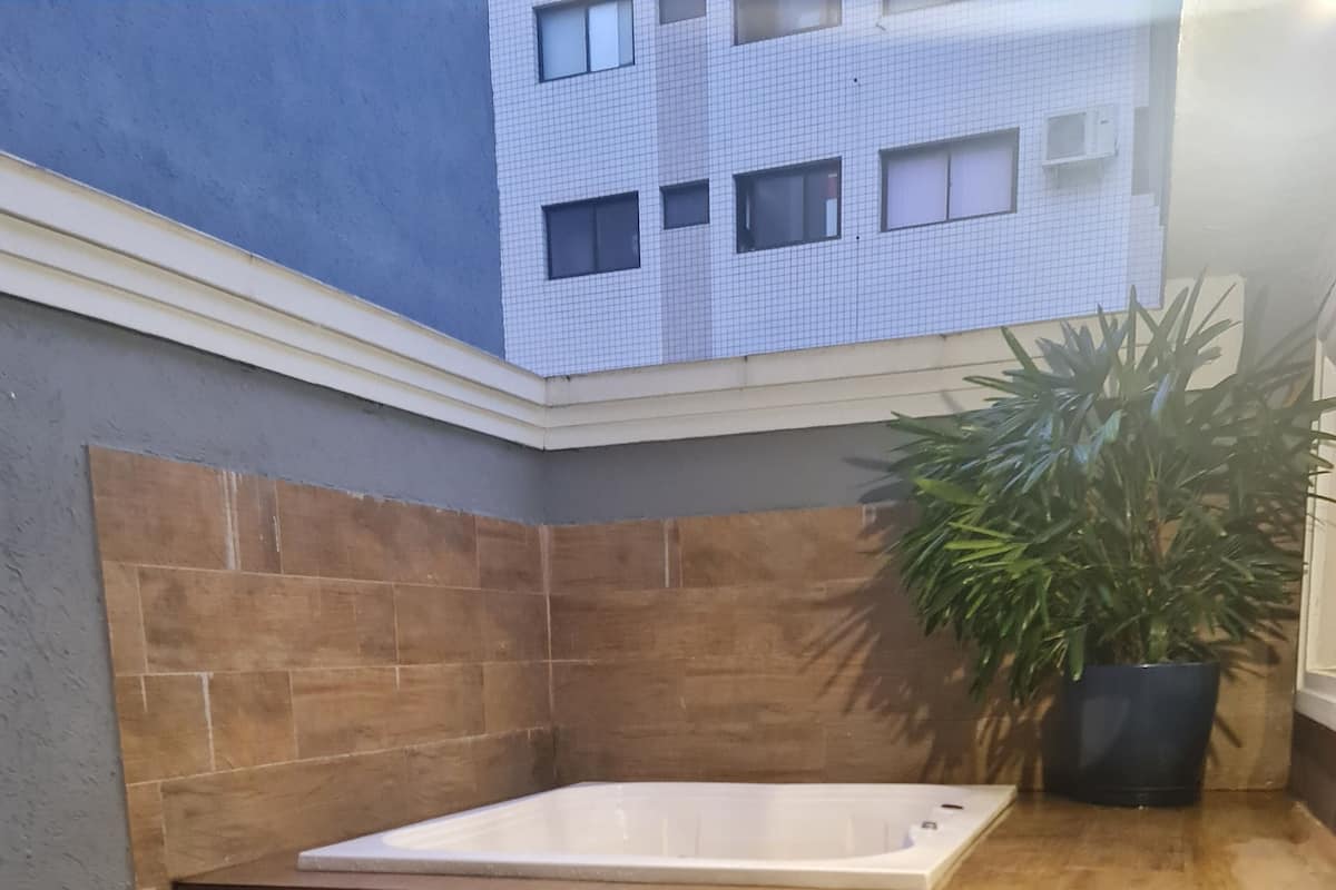 Ein modernes Badezimmer mit einer freistehenden Badewanne, Holzwegen und einem Blumentopf.