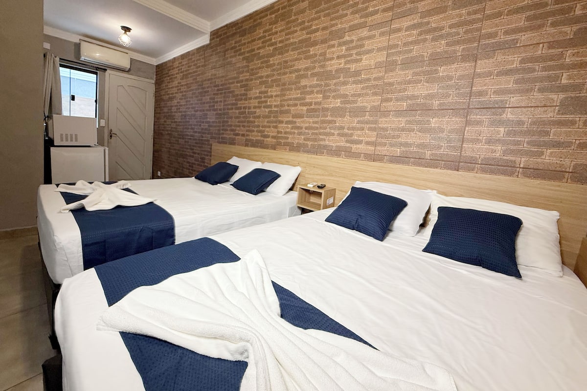 Ein Hotelzimmer mit zwei Betten, einer Ziegelwand und einem Fenster.