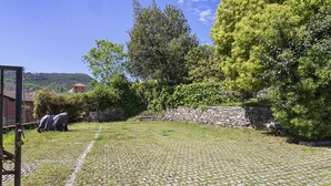 Ein Innenhof mit Kopfsteinpflasterweg, Steinmauer und Grünpflanzen.