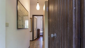 Ein Korridor mit gemustertem Boden, einem gerahmten Bild an der Wand und einer Holztür.