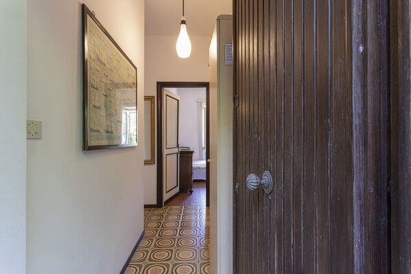 A hallway with patterned flooring, a framed picture on the wall, and a wooden door. - Vintage Apartment With Garden by Wonderful Italy (Santa Margherita Ligure)