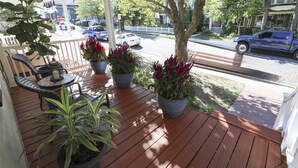 Une véranda en bois agrémentée de plantes en pot et de meubles d’extérieur.
