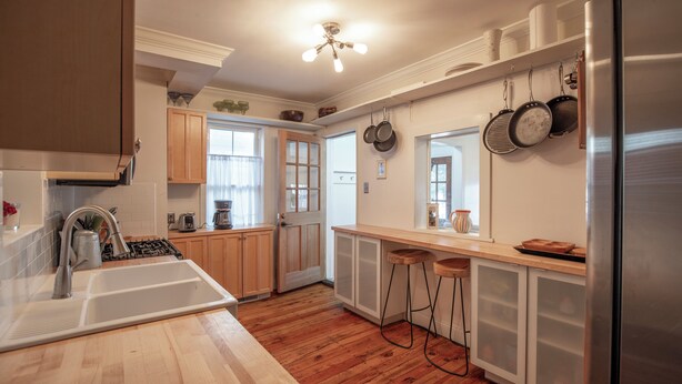 Une cuisine dotée de meubles en bois, d’un réfrigérateur en acier inoxydable, d’un évier et d’un ventilateur de plafond.