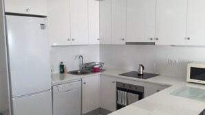 A modern kitchen with white cabinets, a dishwasher, a sink, and a microwave.