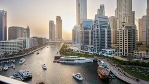 A cityscape with modern high-rise buildings, a marina with boats, and a river. - Deluxe 1BR Corner Suite with Marina Views (Dubai)