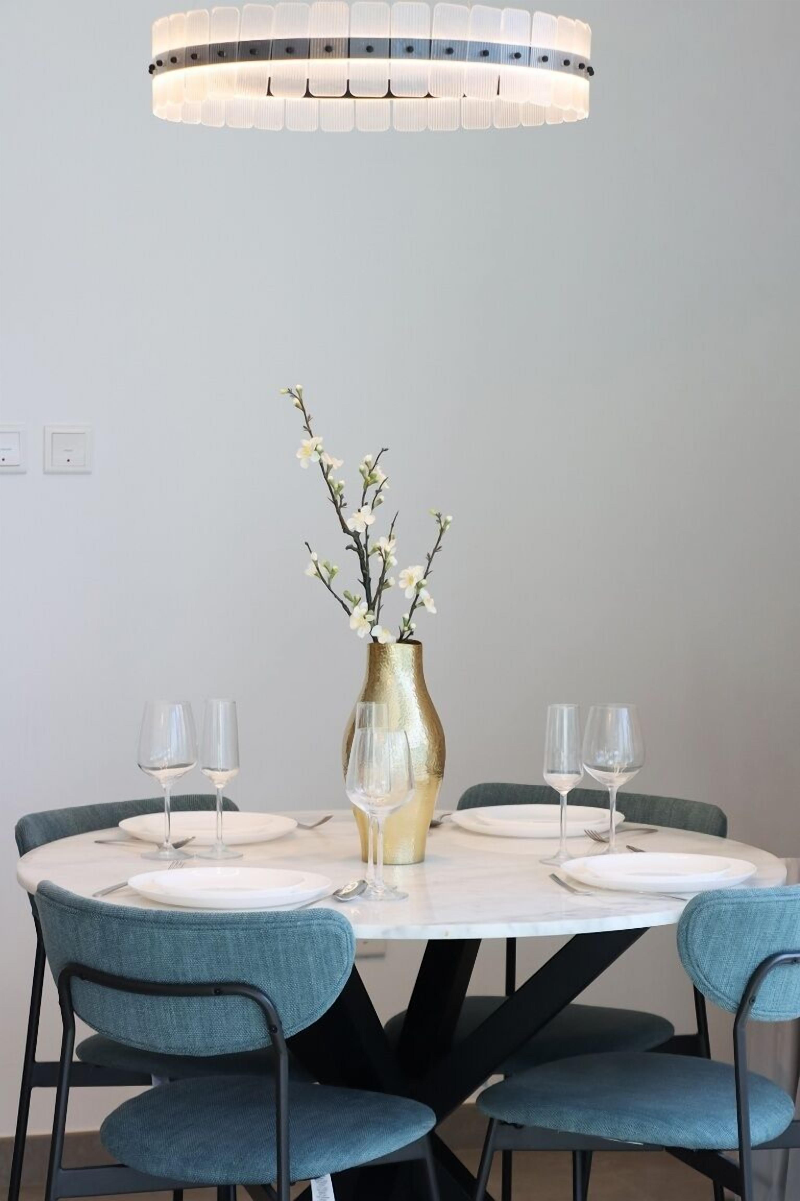Une table à manger avec quatre chaises, un vase rempli de fleurs et deux verres à vin.