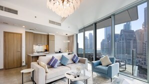 A modern living room with a sofa, armchairs, and a coffee table, featuring a city view through large windows. - Deluxe 1BR Corner Suite with Marina Views (Dubai)