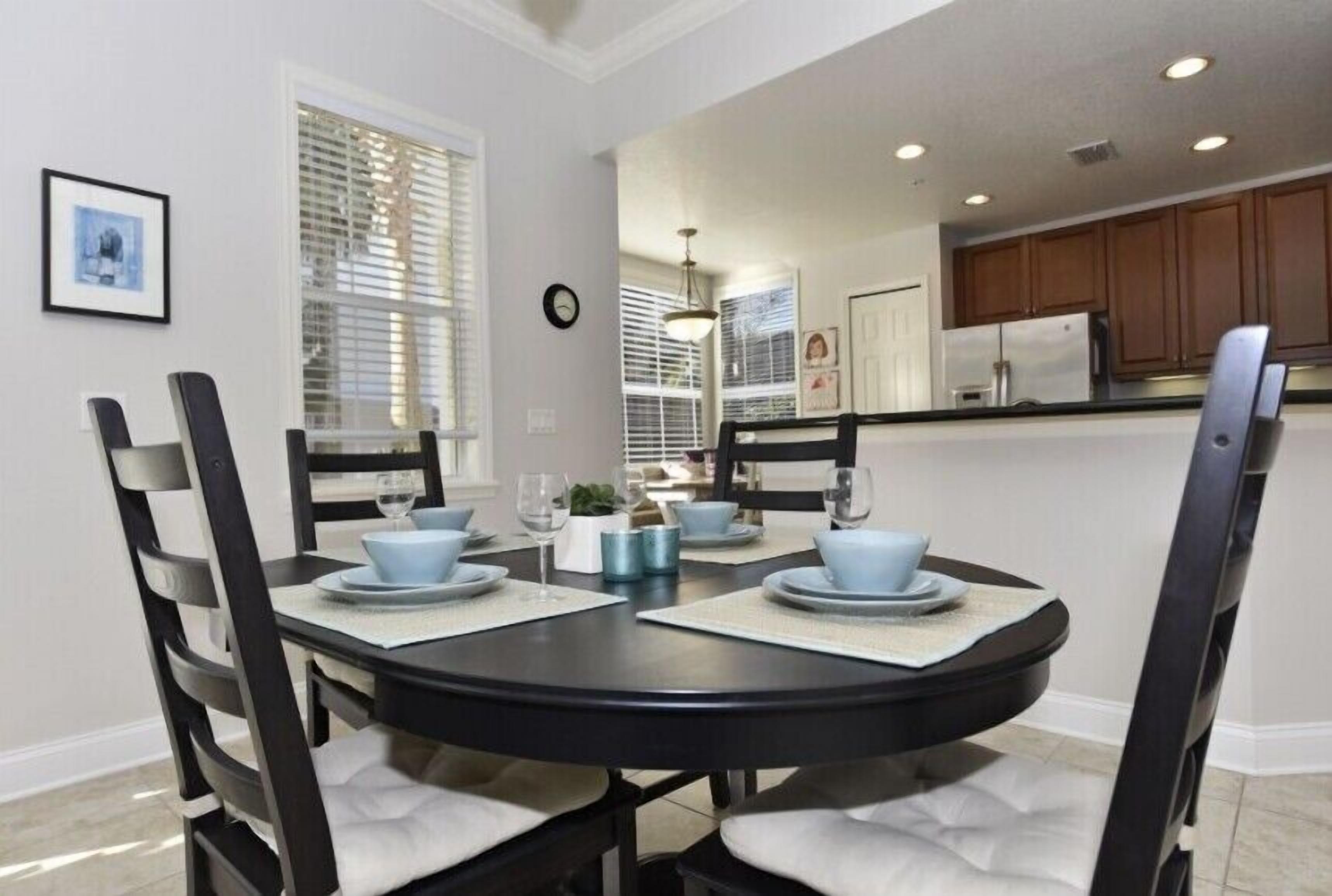 A dining area with a round table set for four, surrounded by chairs with cushioned seats.