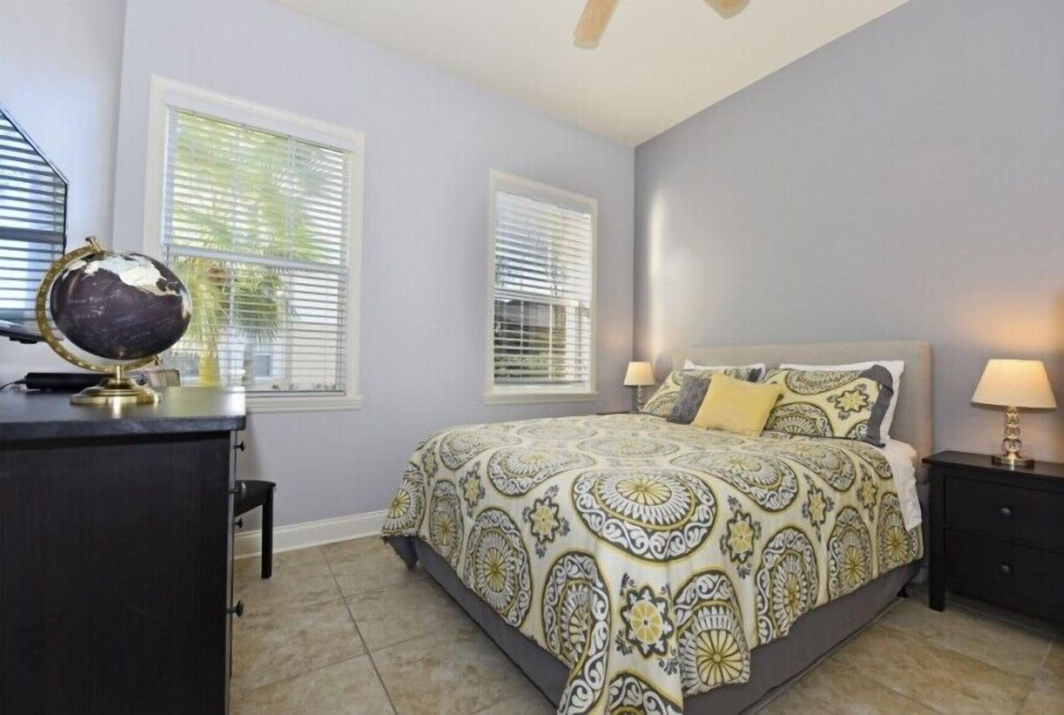 A bedroom with a bed, nightstands, a desk, and a globe.
