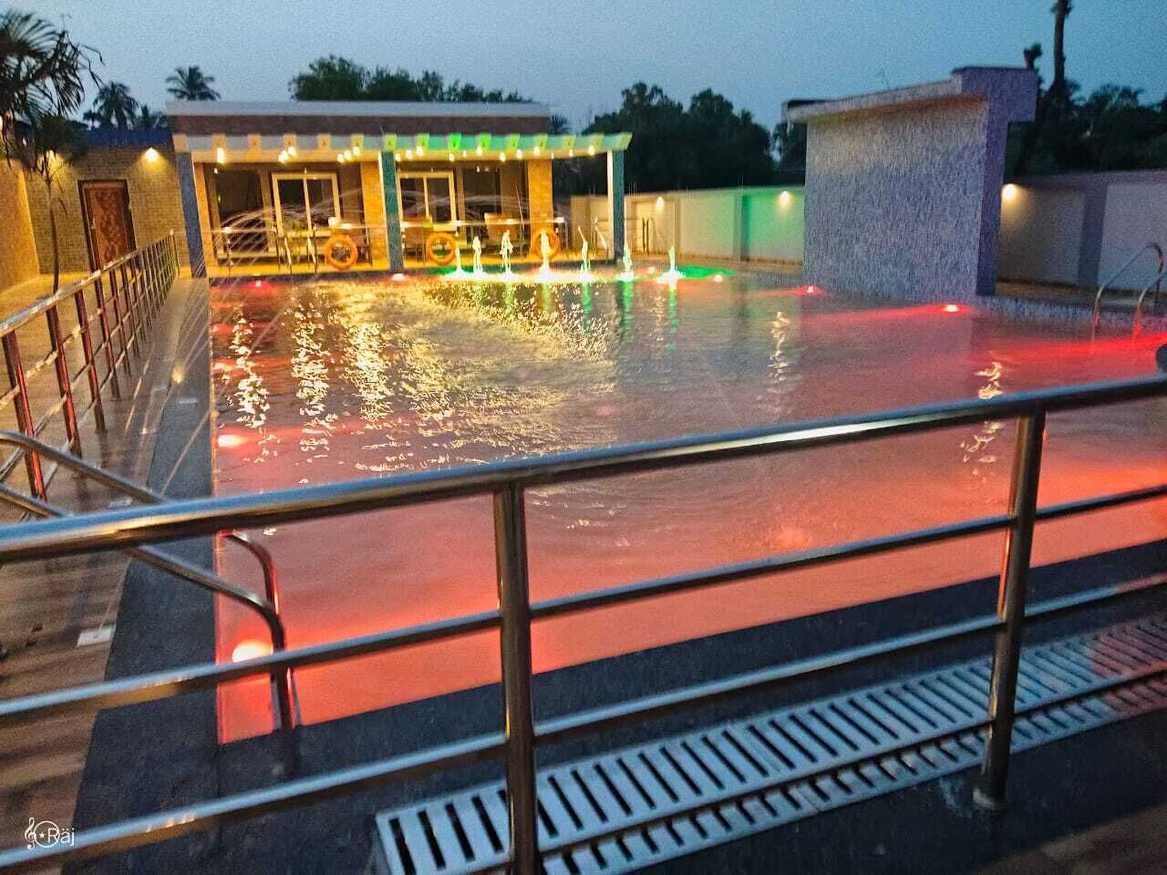 A swimming pool area with a covered seating area and a water fountain.