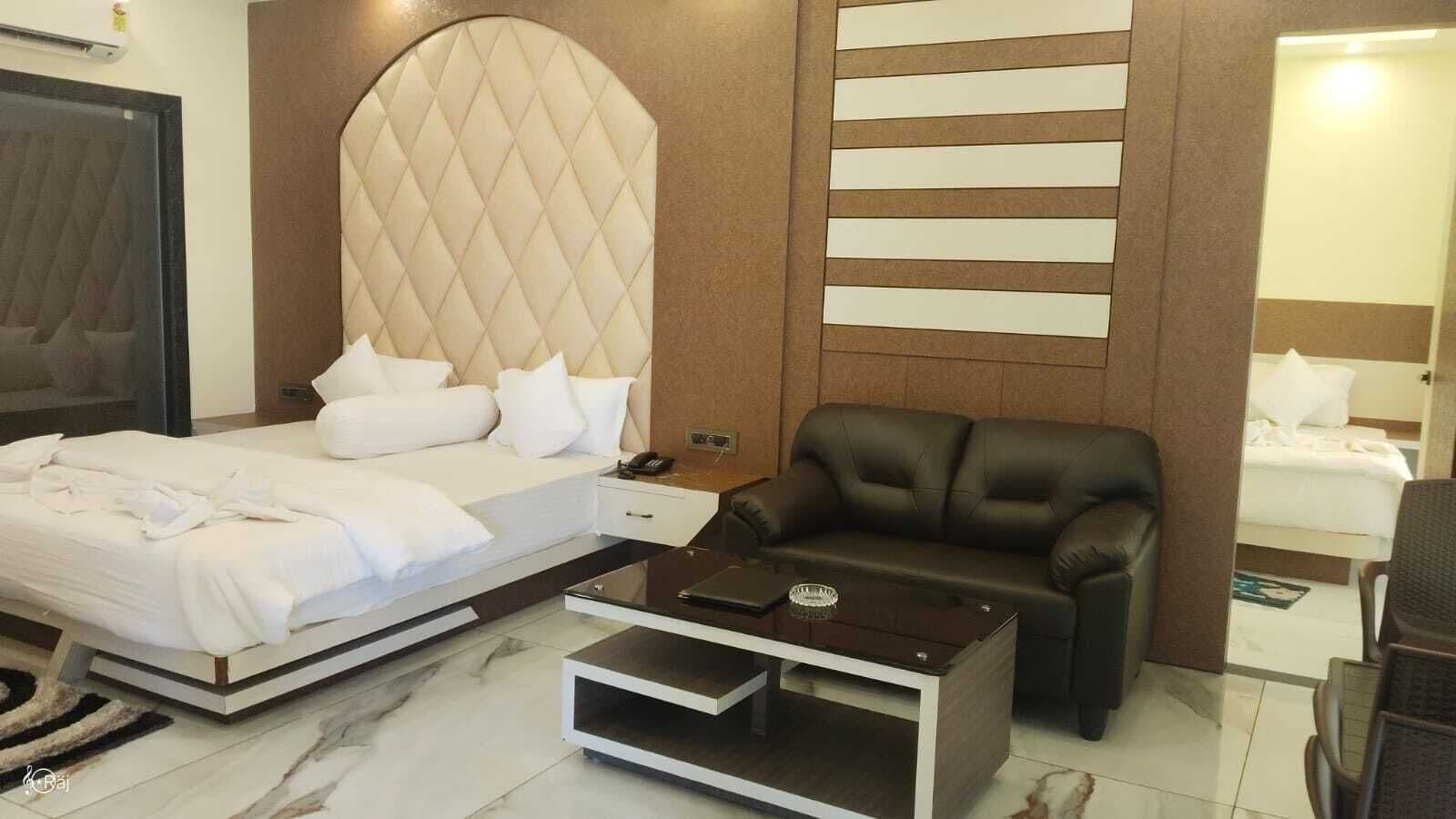 Una habitación de hotel moderna con una cama, un sofá de cuero, una mesa de centro y un espejo grande.