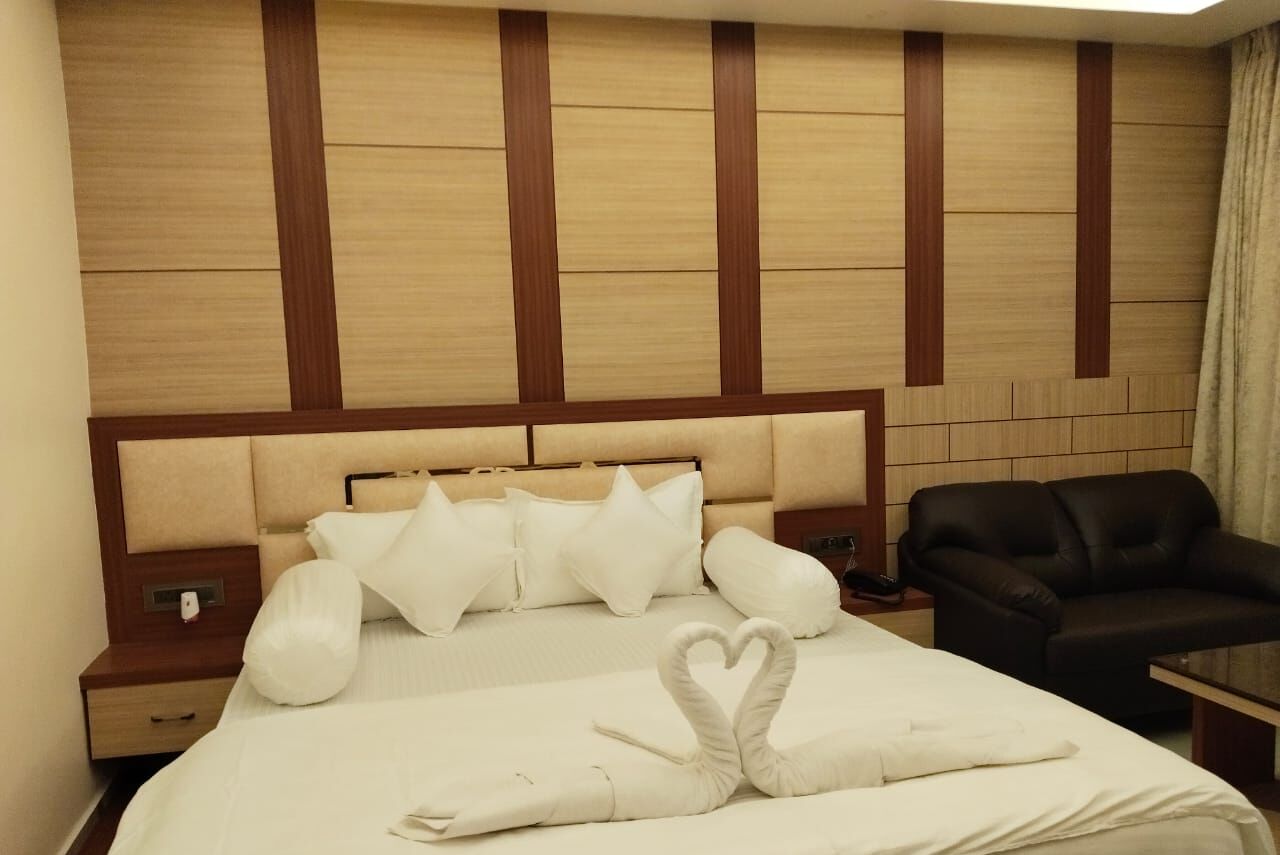 A hotel room with a large bed, a wooden headboard, and a black leather armchair.