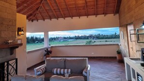 Een gezellige kamer met een houten plafond, een bank, een open haard en uitzicht op het landschap.