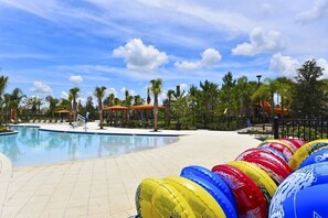 A pool area with lounge chairs and umbrellas, surrounded by palm trees.