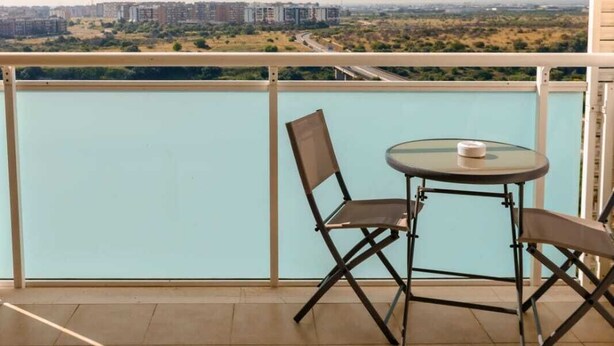 A balcony with a table and chairs, overlooking a cityscape and a body of water. - LUXURY 1 (Bari)