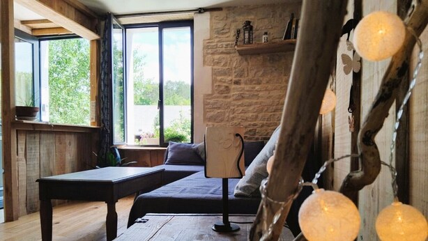Una habitación acogedora con suelo de madera, una cama con cabecera, una mesa y un ventanal con vistas a zonas verdes.