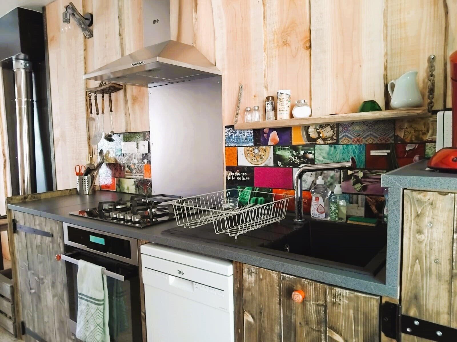 Een keuken met een gasfornuis, vaatwasser en houten keukenkastjes.