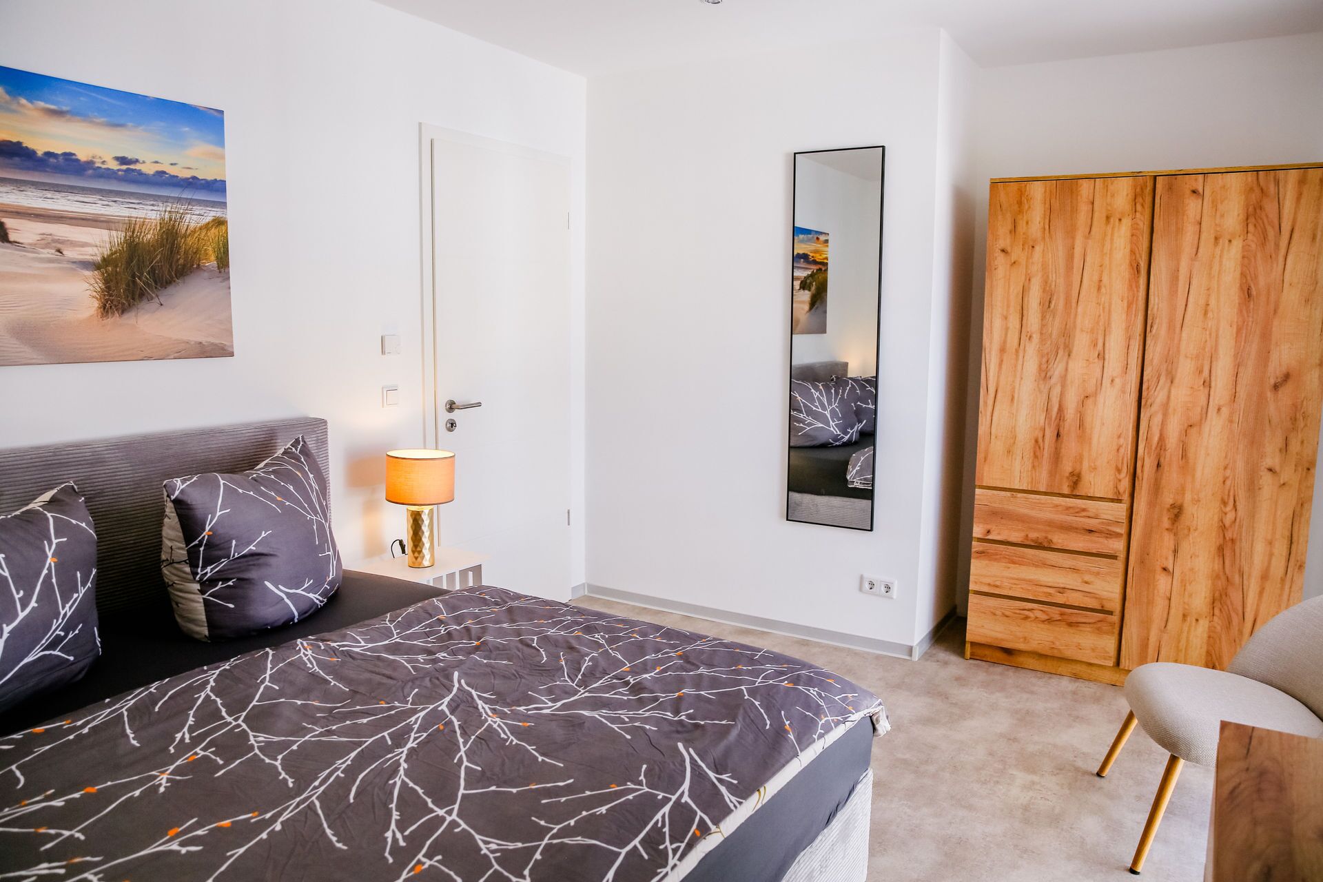 Una camera da letto con un letto, un comodino con una lampada, un armadio e un quadro appeso al muro.