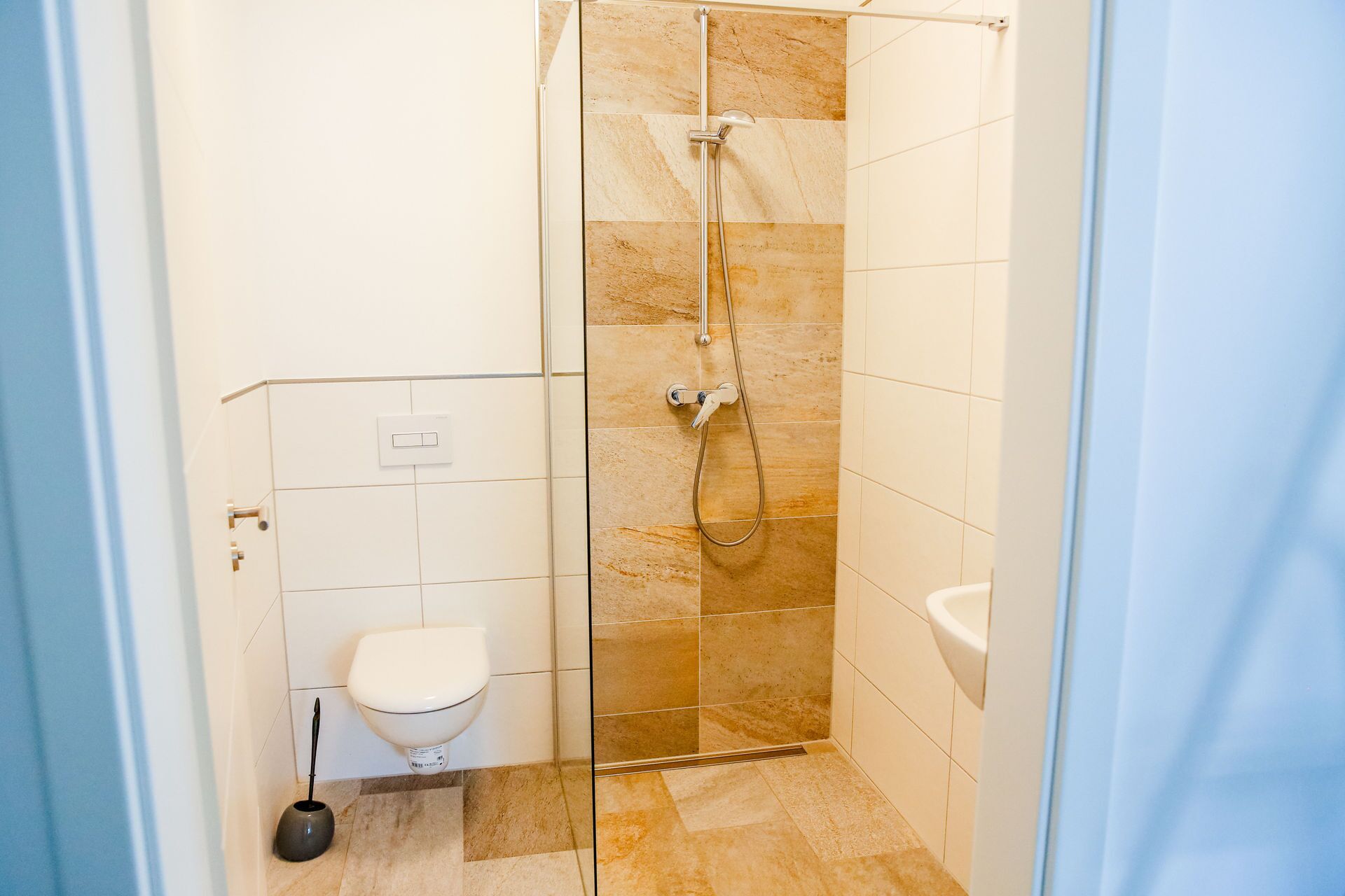 A small, modern bathroom with a glass shower enclosure, a toilet, and a sink.