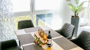 Un comedor con una mesa de madera, cuatro sillas, una botella de vino, copas y velas.