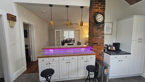 A kitchen with white cabinets, a granite countertop, pendant lights, a clock, and a coffee maker. - Cozy Historic Home just 2 miles from USC, downtown and 6 miles from Ft. Jackson (Columbia)