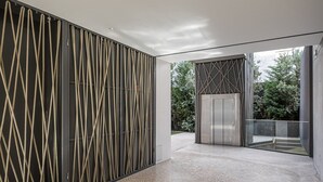 A modern interior with a patterned wall, a glass elevator, and a view of greenery outside. - GuestReady - Urban chic in Aveiro (Aveiro)