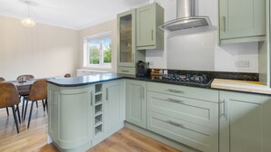 A modern kitchen with light green cabinets, a black countertop, and a stainless steel range hood. - Modern Serenity in Langley Vale (Epsom)