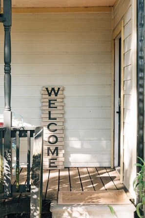 Une véranda en bois avec une pancarte indiquant « BIENVENUE ».