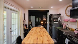 Een moderne keuken met een houten eettafel, inbouwapparatuur en een groot raam.