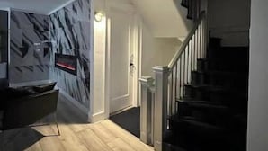 Een modern interieur met een trap, een aan de muur bevestigde televisie en een houten vloer.