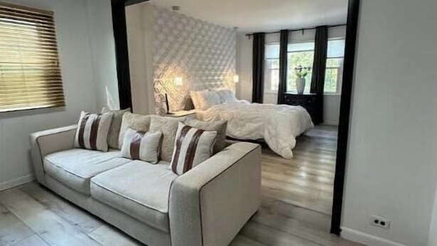 Een moderne slaapkamer met een groot bed, een bank en uitzicht naar buiten door een raam.