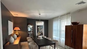 Een moderne eethoek met een donker houten tafel, lichte stoelen en een wit vloerkleed.